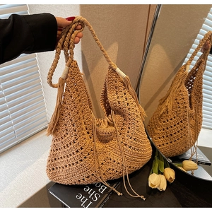 Detail of crochet weave pattern on straw hobo bag with tassel and drawstring liner