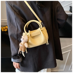 Sac seau jaune pâle à motif crocodile avec pendentif ours porté par un mannequin