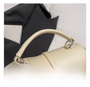Détail de la poignée en cuir et des ferrures métalliques d'un sac à main crème