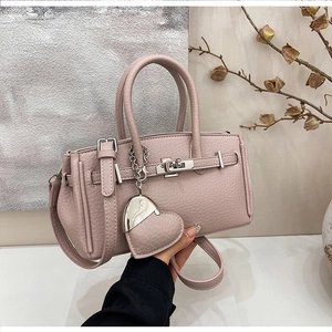 Dettaglio borsa in pelle rosa chiaro con fibbia argentata e ciondolo a forma di cuore