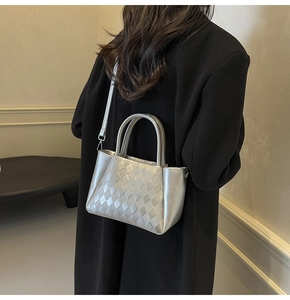 Detail of silver quilted bucket bag worn with black suit for a stylish high-contrast look