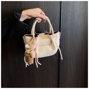 Détail du mini sac seau tissé crème avec charm ours et poignée ronde rigide
