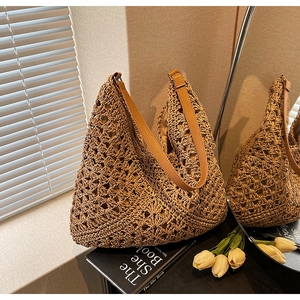 Dettaglio della borsa in paglia intrecciata con tracolla in pelle e fibbie in metallo