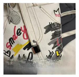 Detail of metal padlock and tennis racket charm on graffiti canvas bucket bag