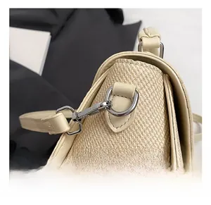 Gros plan du crochet en métal argenté et de la texture tissée de ce sac à bandoulière beige