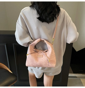 Detail of pink suede crossbody dumpling bag with drawstring and rectangular leather label