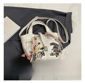 Detail of canvas bucket bag featuring vibrant street graffiti patterns and metal lock accent