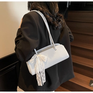 Detail of light blue leather baguette bag with a delicate white lace bow on the side