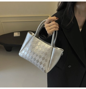 Silver quilted bucket bag with woven pattern and metallic finish held by model