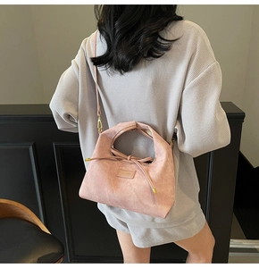Detail of pink crossbody bag with drawstring design shown on a model's shoulder