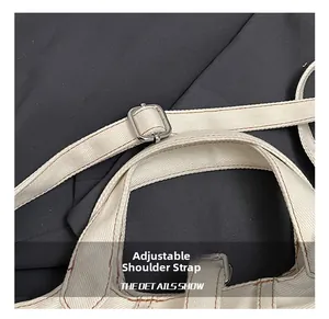 Close-up of adjustable canvas shoulder strap with silver buckle and brown stitching details