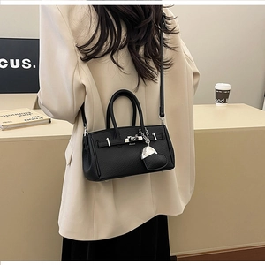 Dettaglio borsa in pelle martellata nera con chiusura argento indossata su blazer bianco