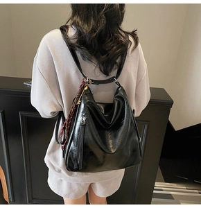Dettaglio dello zaino nero lucido con ciondolo a foulard a righe in stile moderno