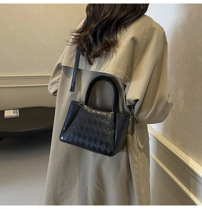 Detail of black quilted woven handbag with sleek leather panels and stylish handle