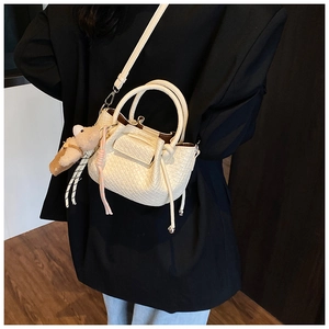 Détail du mini sac sceau plissé blanc avec breloque ours en peluche sur costume noir