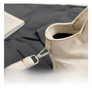 Detailed close-up of silver metal hooks and sturdy stitching on beige canvas bucket bag