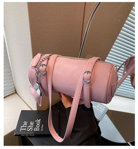 Detail of pink leather barrel bag with silver buckles and heart-shaped pendant charm