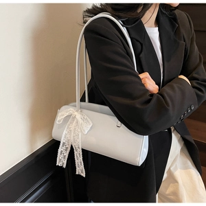 Detail of light blue faux leather underarm bag featuring a delicate white lace bow