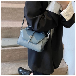 Gros plan du sac bleu clair avec texture tressée et fermoir en métal argenté circulaire
