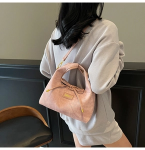 Detailed side view of pink suede shoulder bag with bow and HAMIROO logo on model