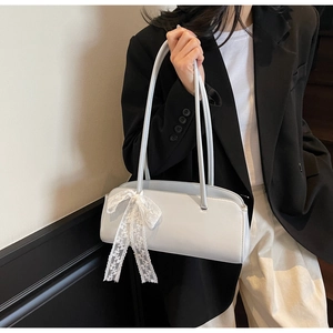 Light gray faux leather shoulder bag with white lace bow detail shown on a black blazer