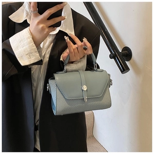 Détail du sac bandoulière bleu-gris clair avec texture tissée géométrique et fermoir argent