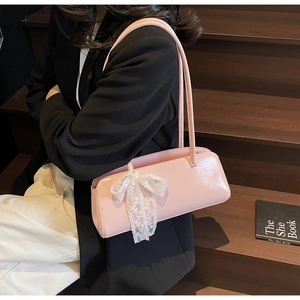 Close-up of pink patent leather pillow bag with delicate white lace bow detail