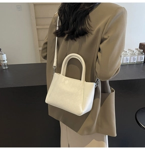 Detail of white woven texture tote bag with silver metal hardware and leather strap