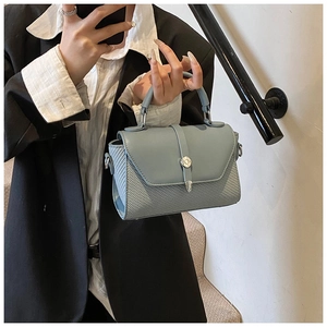 Détail de la texture tissée et du cuir mat sur un sac à main chic avec fermoir en métal