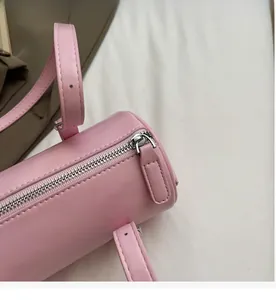 Close-up of smooth silver metal zipper and oil wax leather texture on pink barrel bag