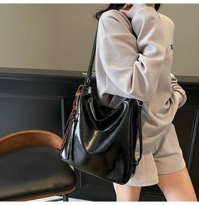 Dettaglio della borsa hobo nera lucida con coulisse intrecciata rossa e finiture argento