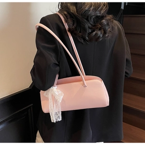Pink faux leather underarm bag featuring a delicate white lace bow accent on a wooden staircase