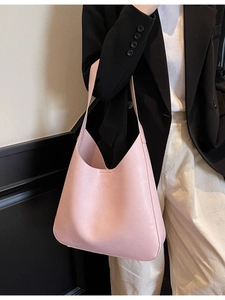 Sac fourre-tout minimaliste en cuir rose clair avec une texture fine porté à l'épaule