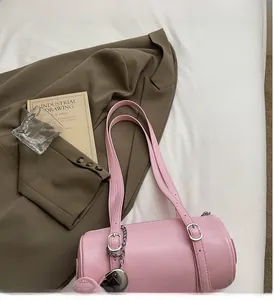 Detail of pink cylindrical leather bag with silver heart charm and adjustable straps