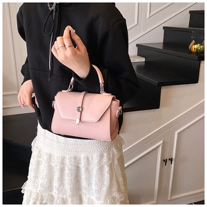 Détail du sac bandoulière rose montrant le fermoir rotatif et le panneau latéral texturé