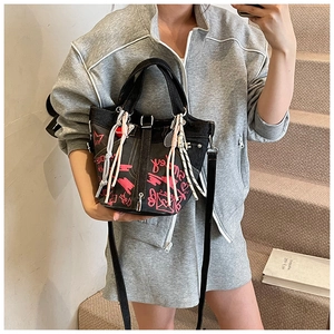 Detail of black denim bucket bag with pink graffiti prints and decorative charms