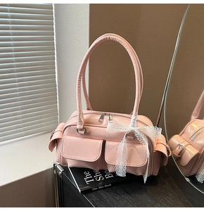 Close-up of pink glossy Boston bag featuring front pockets and lace bow detail