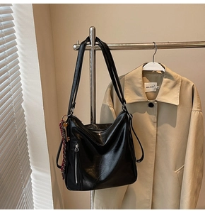 Dettaglio borsa hobo nera con cerniera verticale e ciondolo decorativo intrecciato