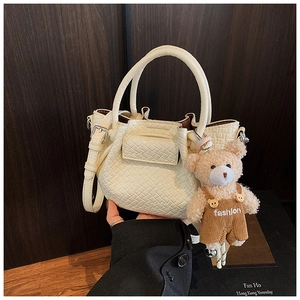 Détail du mini sac seau crème avec texture crocodile et pendentif ours en peluche