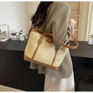 Macro view of woven straw tote bag with brown leather trim and dual handles detail