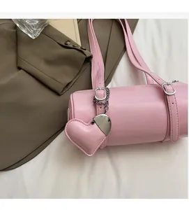 Detail view of pink cylinder handbag with heart pendant and silver metallic buckles