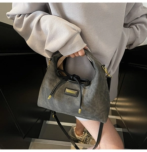 Detail of charcoal grey dumpling bag with bow accent and gold HAMIROO logo