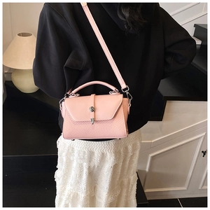 Détail du sac bandoulière rose clair montrant la texture tissée et le fermoir argenté