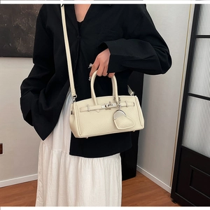 Elegante borsa in pelle color crema con fibbia argentata e ciondolo a cuore su una modella