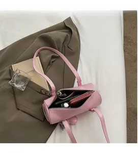 Detail view of pink cylinder bag interior showing capacity with cards and cosmetics