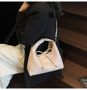 Detail of pink corduroy handbag featuring a bow ornament and adjustable shoulder strap