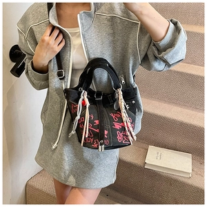 Detail of black denim bucket bag with pink graffiti patterns and silver twist lock closure
