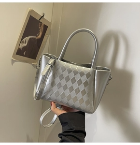 Close-up of silver textured handbag with diamond quilted pattern and metal handle