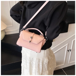 Sac bandoulière rose avec texture tissée et élégant fermoir cylindrique en métal