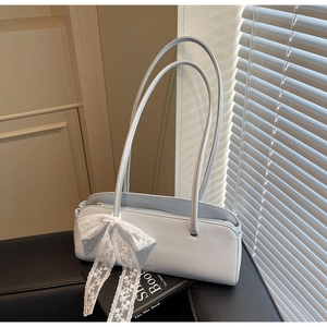 Close-up of light blue leather shoulder bag featuring delicate white lace bow detail